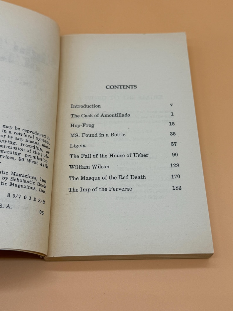 May include: An open book showing the contents page. Titles include "The Cask of Amontillado" and "The Fall of the House of Usher." The book is open on a light beige surface.