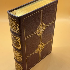 May include: A brown leather-bound book with gold accents and the title "Tom Jones" on the spine.