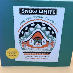May include: A teal book titled "Snow White and the Seven Dwarfs" with a colorful illustration of a cottage. The cover features the text "Snow White" in a black box and "And the Seven Dwarfs" in a curved line. The book is translated and illustrated by Wanda Gag.