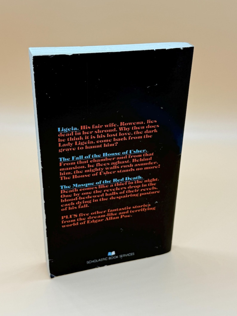 May include: A paperback book with a black cover. The text on the cover details stories by Edgar Allan Poe, including "Ligeia" and "The Fall of the House of Usher." Published by Scholastic Book Services.