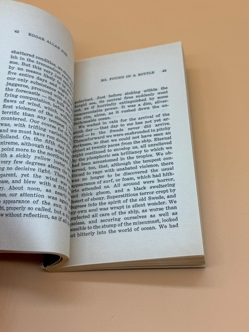 May include: An open book displaying text from "MS. Found in a Bottle" by Edgar Allan Poe. The pages are off-white with black text. The book is open to pages 42 and 43.
