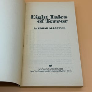 May include: An open book displaying the title "Eight Tales of Terror" by Edgar Allan Poe. The book has an off-white cover with black lettering. The Scholastic Book Services logo and locations are printed at the bottom.