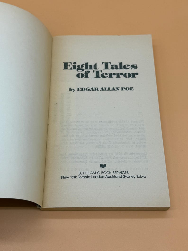 May include: An open book displaying the title "Eight Tales of Terror" by Edgar Allan Poe. The book has an off-white cover with black lettering. The Scholastic Book Services logo and locations are printed at the bottom.
