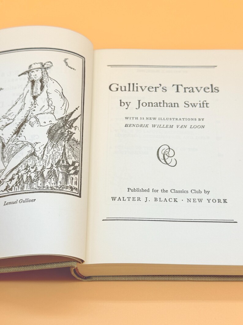 May include: An open book with the title "Gulliver's Travels" by Jonathan Swift. The book has illustrations and text. The publisher is Walter J. Black, New York. The left page shows an illustration of Lemuel Gulliver.