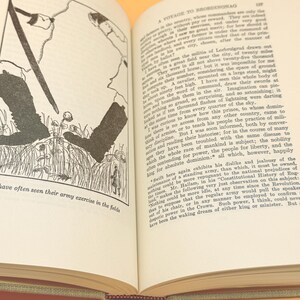 May include: Open book with text and a black and white illustration of figures in a field. The text reads "A Voyage to Brobdingnag" and describes military exercises. The book is open to a double-page spread.