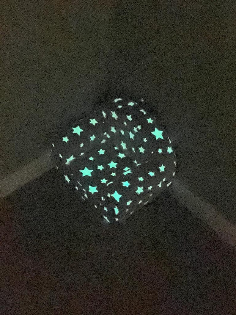 Puede incluir: Una tela estampada en blanco y negro con un dise&ntilde;o que brilla en la oscuridad con estrellas blancas sobre un fondo negro.