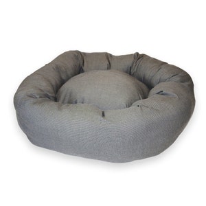 May include: A grey, round pet bed with a raised rim and a soft, plush interior. The bed is made of a durable fabric and is perfect for providing a comfortable and cosy sleeping space for your pet.
