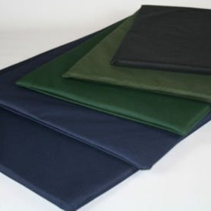 May include: An assortment of rectangular cushions in various sizes and colors. The cushions are stacked, showcasing shades of navy blue, green, and black. The cushions appear to be made of a smooth, possibly waterproof material.