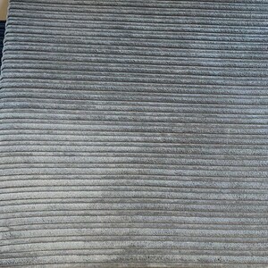 May include: Close-up of a gray corduroy fabric with a ribbed texture.