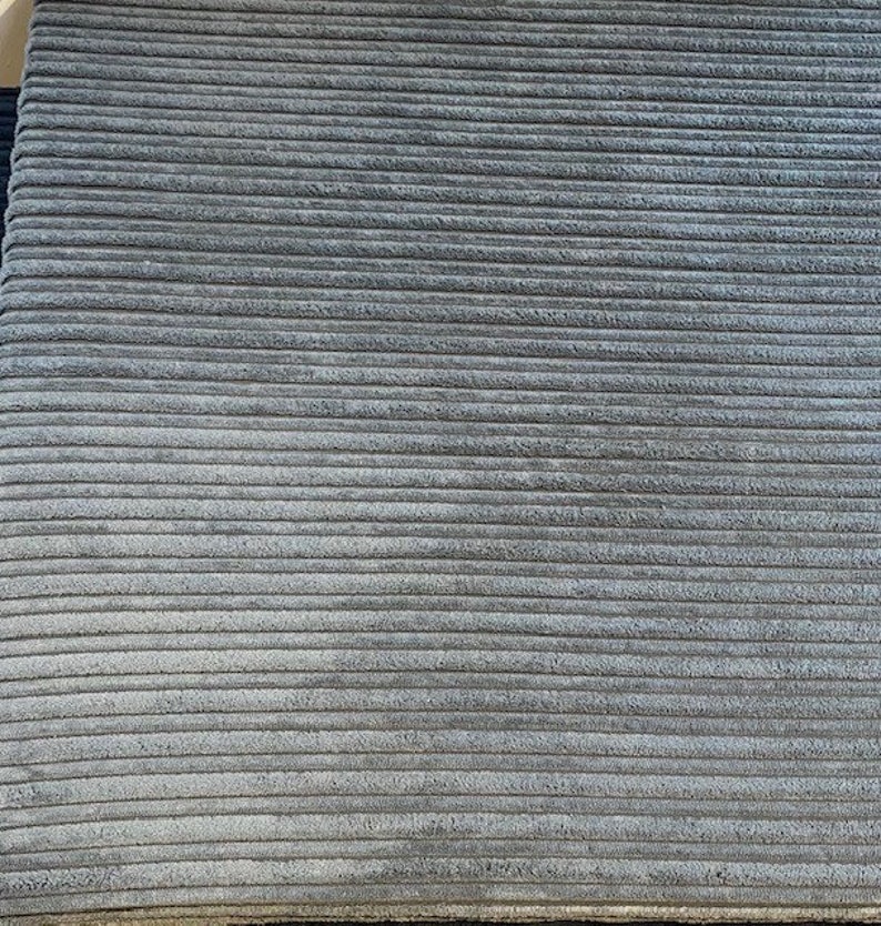May include: Close-up of a gray corduroy fabric with a ribbed texture.