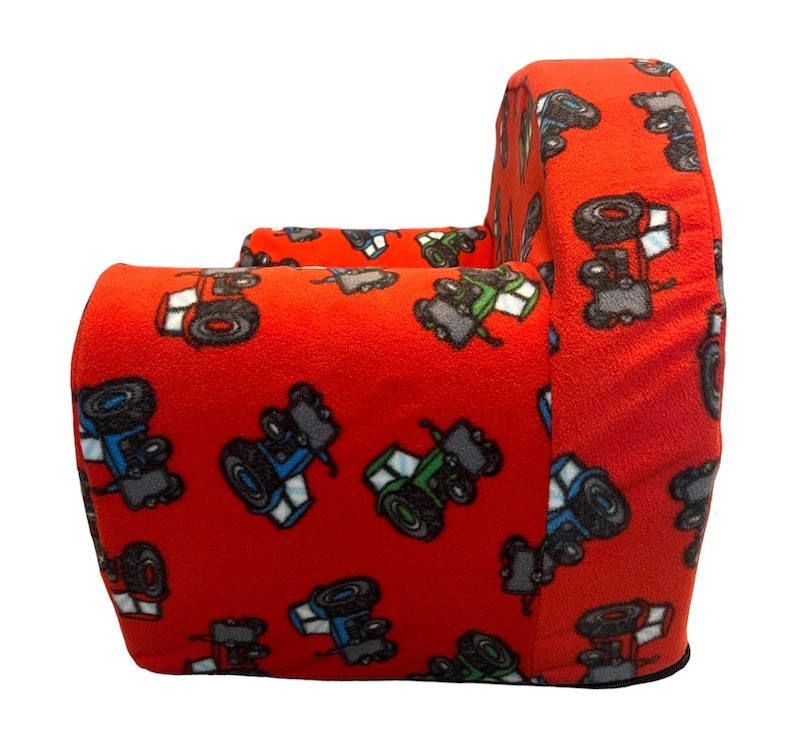 Puede incluir: Sill&oacute;n rojo para ni&ntilde;os con estampado de tractor. El sill&oacute;n est&aacute; hecho de tela suave y tiene un respaldo y brazos redondeados.