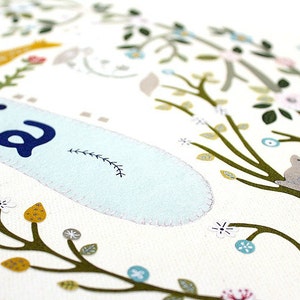 May include: A white background with a blue and white banner that says "Olivia" with a small green vine design. The banner is surrounded by a green tree with brown branches and leaves, yellow and white flowers, and a small gray rabbit sitting on a branch.