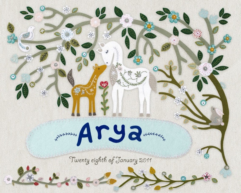 May include: A white and brown felt applique of a horse and foal standing under a green and white felt tree with flowers. The name "Arya" is written in blue felt below the animals. The date "Twenty eighth of January 2011" is written in black felt below the name.