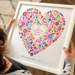 Può includere: Una stampa incorniciata bianca con un design a cuore floreale colorato. Il cuore è pieno di fiori, foglie e altri elementi decorativi. Il testo all'interno del cuore dice "To our wonderful teacher Mrs. Chatterton Thank You". Il testo sotto il cuore dice "With love from Year 5 2021".