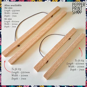 May include: Two sets of light-colored wooden poster hangers with dark brown hanging cords. Text indicates A2 size is 440mm x 20mm x 7mm, A1 is 600mm x 20mm x 7mm, A3 is 320mm x 20mm x 7mm, and A4 is 220mm x 20mm x 7mm. Pepper Print Shop logo.