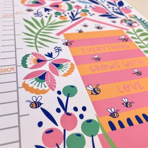 May include: A colorful height chart with floral and bee illustrations. The chart features the words "Everything Grows With Love" and "Kind". The design includes a measurement scale in centimeters.