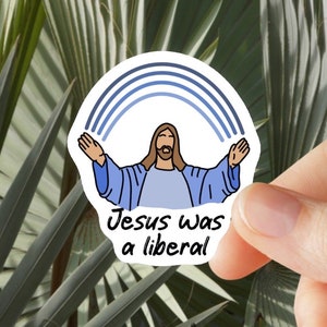 May include: A white sticker with a blue rainbow and a cartoon drawing of Jesus with the text "Jesus was a liberal".