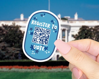 May include: A light blue sticker with the words "REGISTER TO VOTE" and a QR code. The sticker is decorated with white flowers and held in front of the White House.