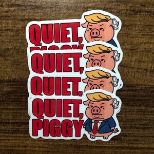 May include: A stack of white stickers with a cartoon pig wearing a suit and a blonde comb-over. The stickers have the words "QUIET, PIGGY" in red block letters.