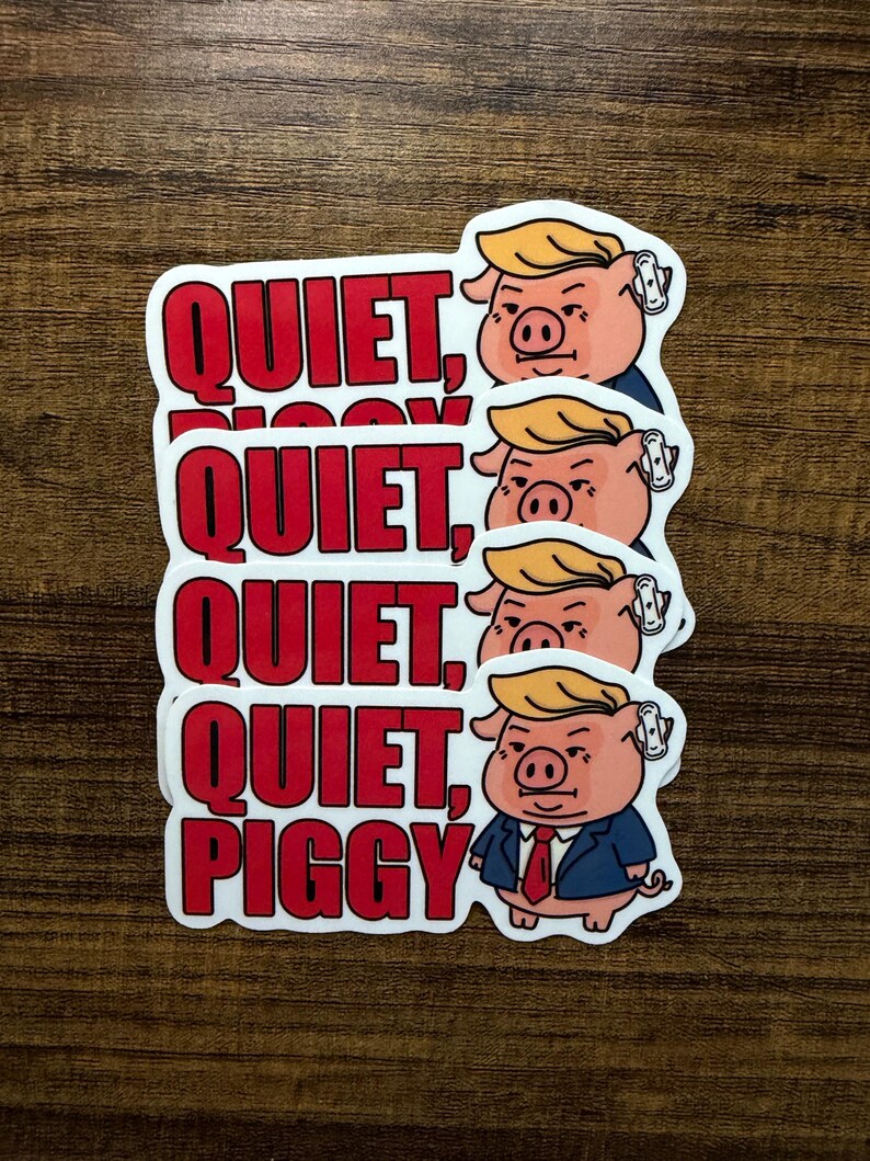 May include: A stack of white stickers with a cartoon pig wearing a suit and a blonde comb-over. The stickers have the words "QUIET, PIGGY" in red block letters.