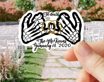 May include: A die-cut sticker featuring two black and white skeletal hands performing a pinky promise, linked by two gold wedding rings and a small diamond icon. The text reads 'til death', 'The McKeans', and 'January 18, 2020' in black script.