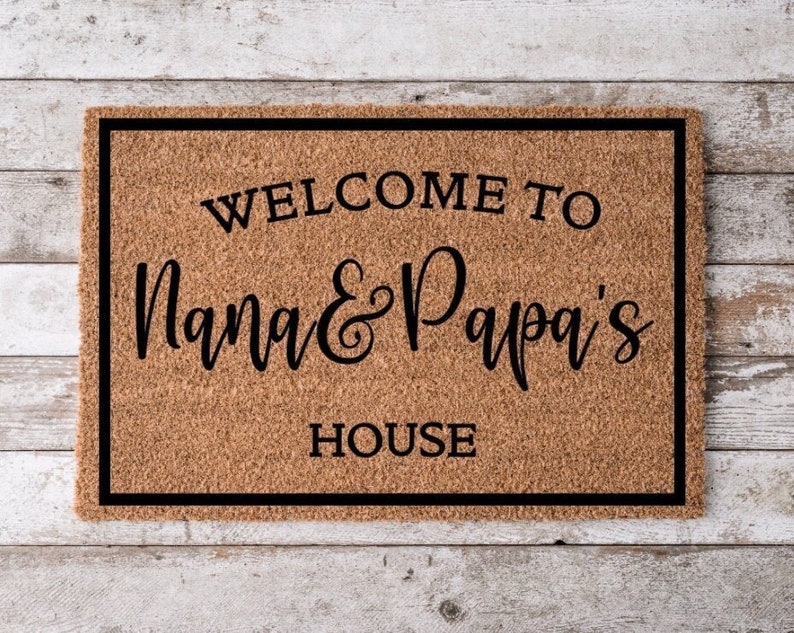 May include: A brown coir doormat with a black border and the text "Welcome to Nana & Papa's House" in black lettering.