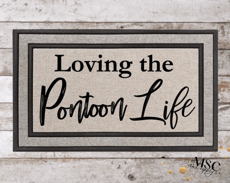 May include: Rectangular doormat with a grey border and the text "Loving the Pontoon Life" in black script. The background is a light beige colour, and the mat has a textured appearance. The doormat is designed for outdoor use.