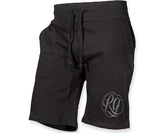 May include: Black athletic shorts featuring an elastic waistband with a drawstring closure. The shorts include side pockets and a circular logo on the lower left leg with the stylized letters RG in a light gray, cursive font design.
