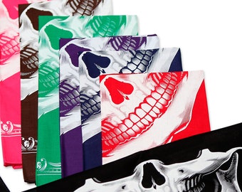 May include: A collection of rectangular fabric bandanas arranged in a fan pattern, each featuring a graphic print of a human skull jawline. The bandanas are available in various solid background colors including pink, brown, green, purple, blue, red, and black.