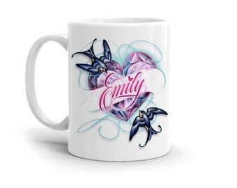 May include: White ceramic mug featuring a heart-shaped design with a pink and purple gemstone pattern. Two swallows and the name "Emily" in cursive are also featured on the mug.