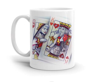 May include: White ceramic mug with a design of playing cards, featuring the Queen of Hearts and the King of Hearts. The cards are in a romantic pose, with the King holding a red heart.