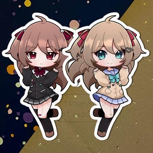 Puede incluir: Dos pegatinas de estilo anime con personajes femeninos jóvenes. Una lleva uniforme escolar negro con lazo rojo, la otra chaqueta beige y falda azul. Ambas tienen ojos grandes y están sobre un fondo azul oscuro y dorado.