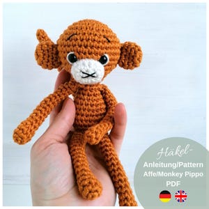 Könnte beinhalten: Häkelanleitung für ein braunes Affen-Amigurumi-Spielzeug namens Pippo. Das Muster ist sowohl in englischer als auch in deutscher Sprache verfügbar. Das Muster ist ein PDF-Download.