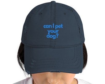 Może przedstawiać: Niebieska, zniszczona czapka bejsbolówka z haftowanym napisem "can I pet your dog?" w kolorze niebieskim.