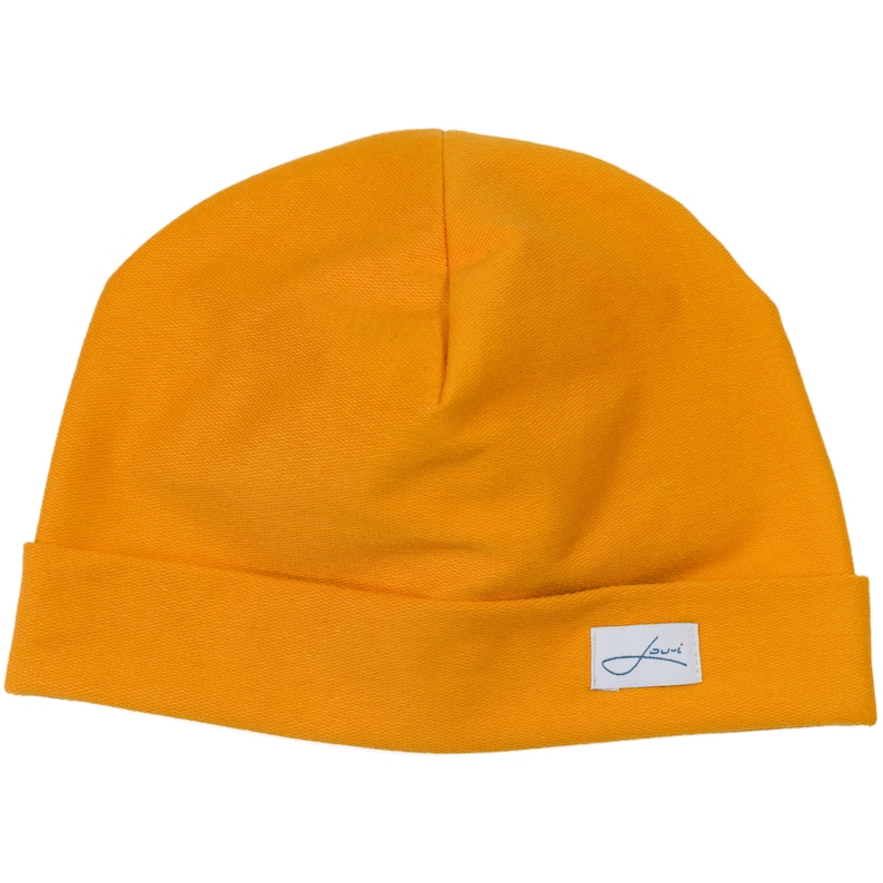 Puede incluir: Gorro de color amarillo mostaza con un borde doblado. Una peque&ntilde;a etiqueta rectangular blanca con texto en cursiva est&aacute; cosida en el borde. El gorro est&aacute; hecho de una tela de punto suave.