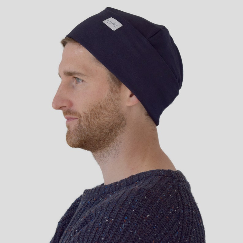 May include: A navy blue beanie with a small white label on the side. The beanie is made of a soft, comfortable fabric and is perfect for keeping your head warm.
