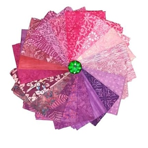 May include: A circular arrangement of fabric swatches in various shades of pink, magenta, and purple, featuring diverse patterns such as floral, geometric, and abstract prints. A single, faceted, bright green circular gem sits at the centre.