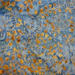 Op de afbeelding: Blauw en gouden batikstof met een bladmotief. De stof heeft een subtiele glans en een zachte, vloeiende textuur.