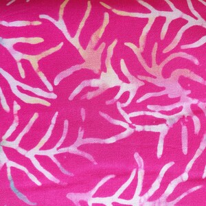 May include: A vibrant hot pink fabric featuring a repeating white coral or branch-like pattern. The design includes subtle, soft gradients of light blue and pale yellow within the white shapes, creating a textured, batik-style appearance.