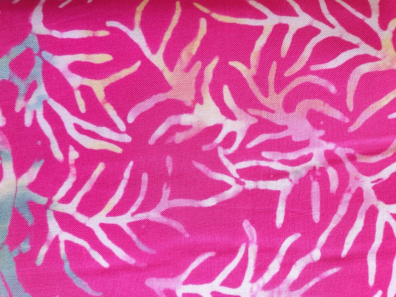 May include: A vibrant hot pink fabric featuring a repeating white coral or branch-like pattern. The design includes subtle, soft gradients of light blue and pale yellow within the white shapes, creating a textured, batik-style appearance.