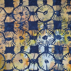 May include: Close-up of a fabric featuring a repeating floral pattern. The flowers are in shades of yellow and orange, set against a dark blue background. The design has a batik-like appearance.