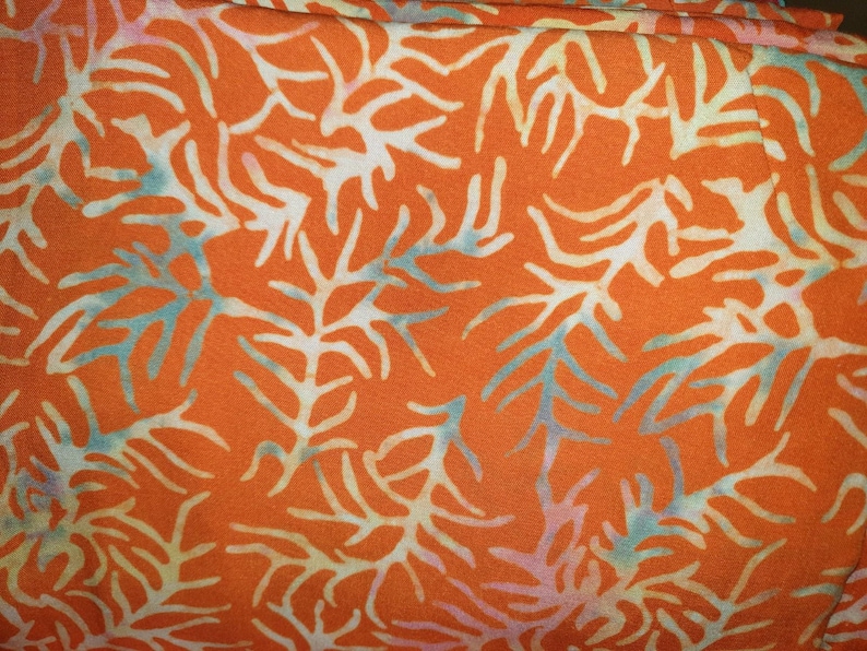 May include: A vibrant orange fabric featuring a repeating pattern of white, branching coral-like shapes. The design includes subtle, soft blue and light purple highlights integrated into the edges of the white organic, tree-like motifs.