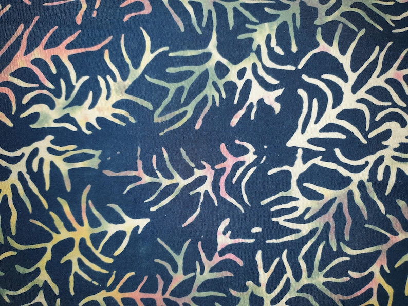 May include: A dark navy blue fabric featuring a repeating batik-style pattern of branching coral or seaweed shapes. The organic, tree-like forms are rendered in soft, blended gradients of pale yellow, light pink, and muted sage green colors.