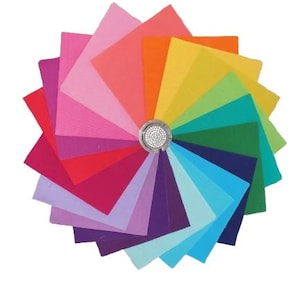 Puede incluir: Un abanico colorido de muestras de tela dispuestas en un patrón circular. Las muestras muestran un espectro de colores, desde rosas y rojos hasta verdes y azules, con un adorno plateado y de pedrería en el centro. Las muestras están dispuestas radialmente.