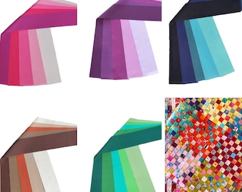 May include: A collection of colorful fabric table runners in various shades of pink, purple, blue, brown, and green. The runners are arranged in a fan-like pattern, showcasing the different color gradients. A patchwork quilt is also visible.