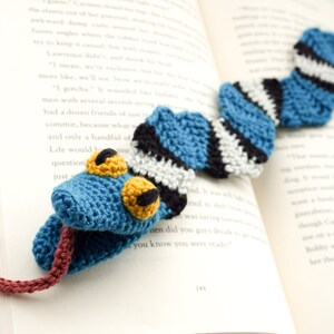 Pu&ograve; includere: Un segnalibro a forma di serpente all'uncinetto blu, bianco e nero con occhi gialli. La lingua del serpente &egrave; di colore bordeaux all'uncinetto.
