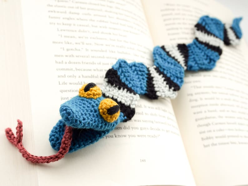Pu&ograve; includere: Un segnalibro a forma di serpente all'uncinetto blu, bianco e nero con occhi gialli. La lingua del serpente &egrave; di colore bordeaux all'uncinetto.