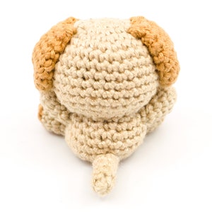 May include: A crocheted beige dog toy with brown ears and a tail.