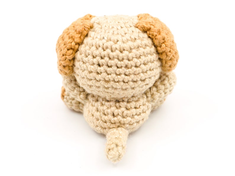 May include: A crocheted beige dog toy with brown ears and a tail.