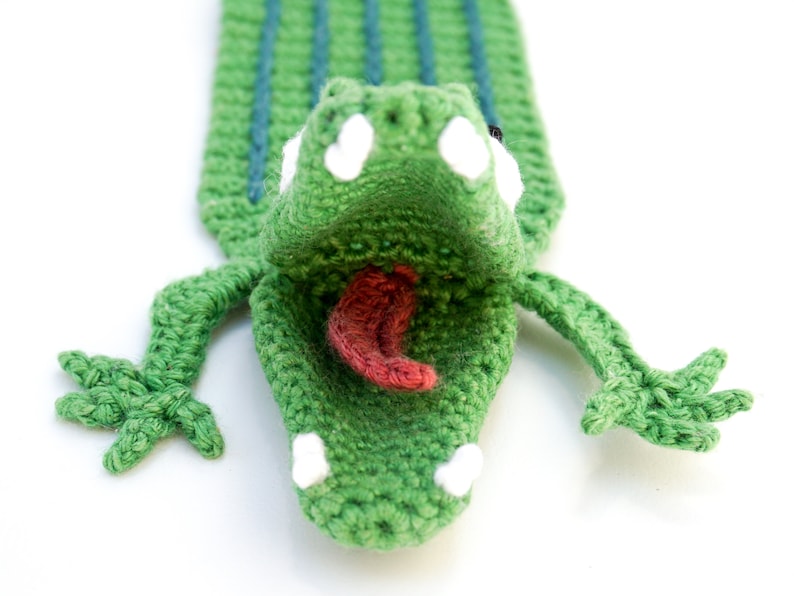Puede incluir: Marcap&aacute;ginas de cocodrilo verde tejido a crochet con la boca muy abierta, dientes blancos y una lengua rosa.